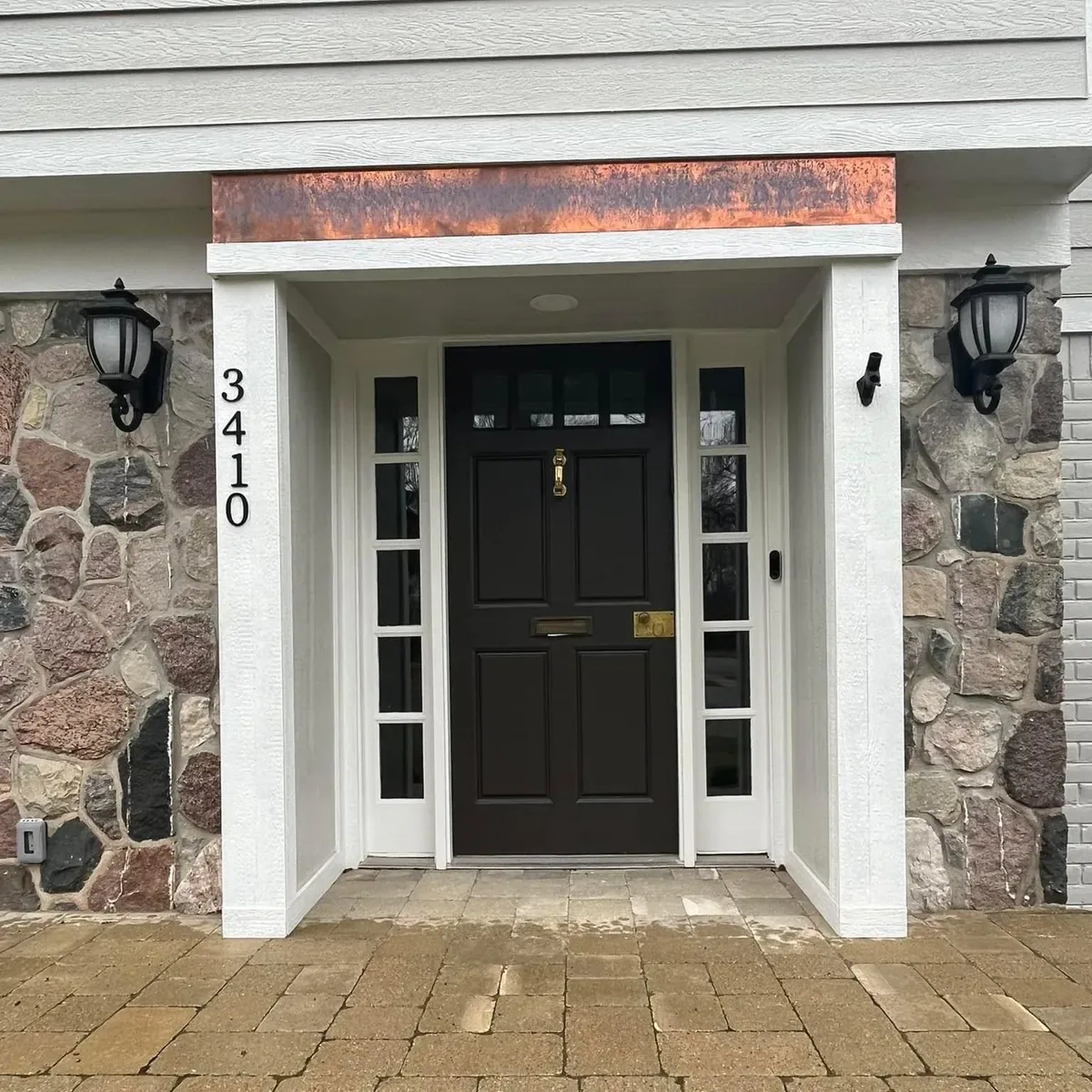 Stone-front entry with a newly painted black front door and white trim