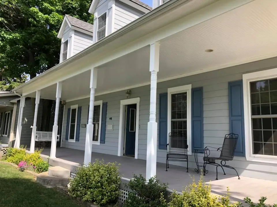 Covered front porch with freshly painted white columns and gray siding