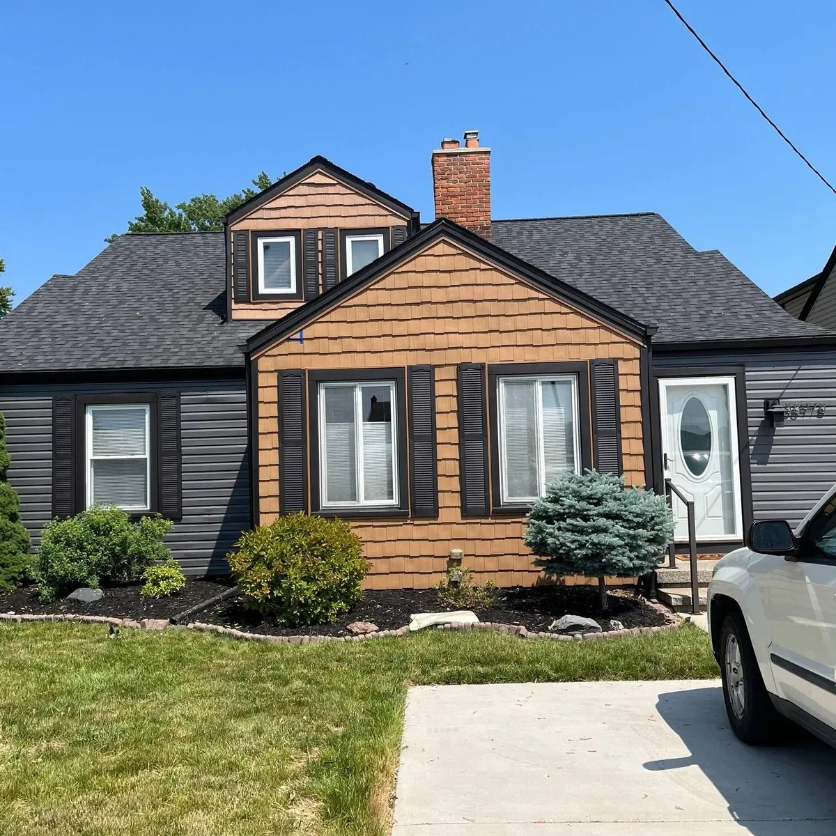 Wood-sided cottage with a black roof and freshly painted exterior
