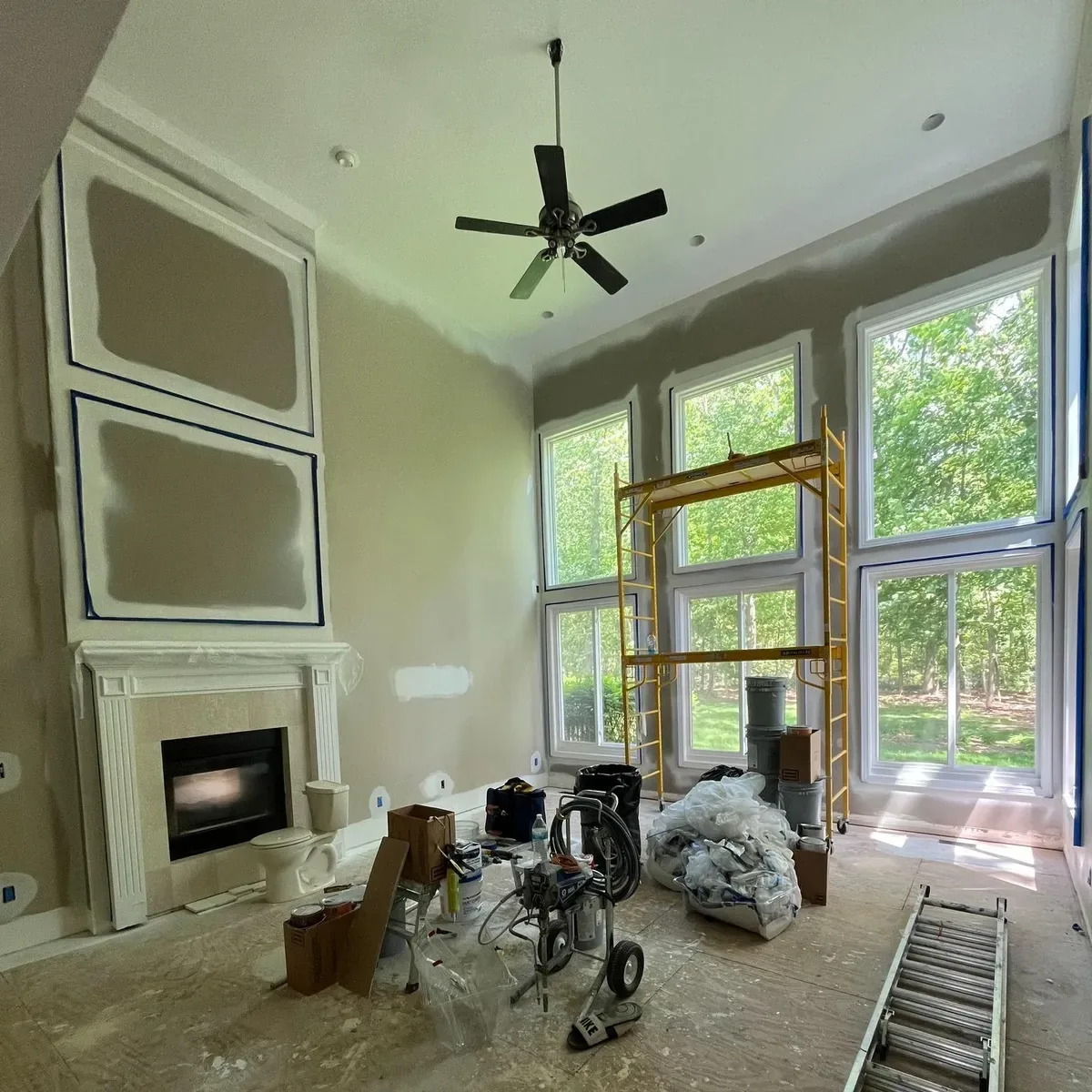 Great room with a fireplace and tall windows prepped and painted by Prime Example Painting